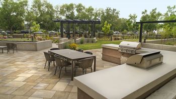 A patio with a grill and a table with chairs